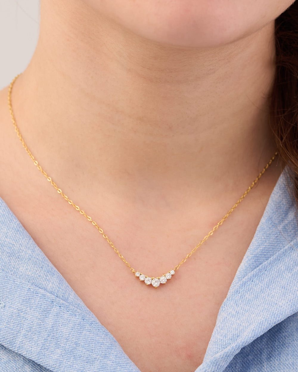 Stainless steel gold-tone dainty necklace with curved crystal bar pendant on neck