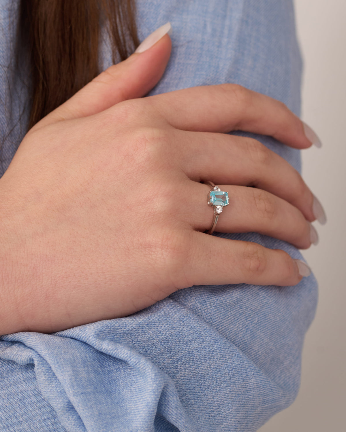 Stainless steel silver-tone solitaire ring with aqua blue gemstone worn on hand