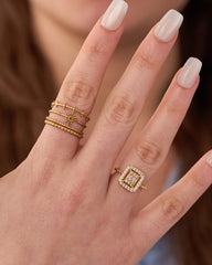 Stainless steel gold-tone stacking rings set with square halo cocktail ring worn on hand