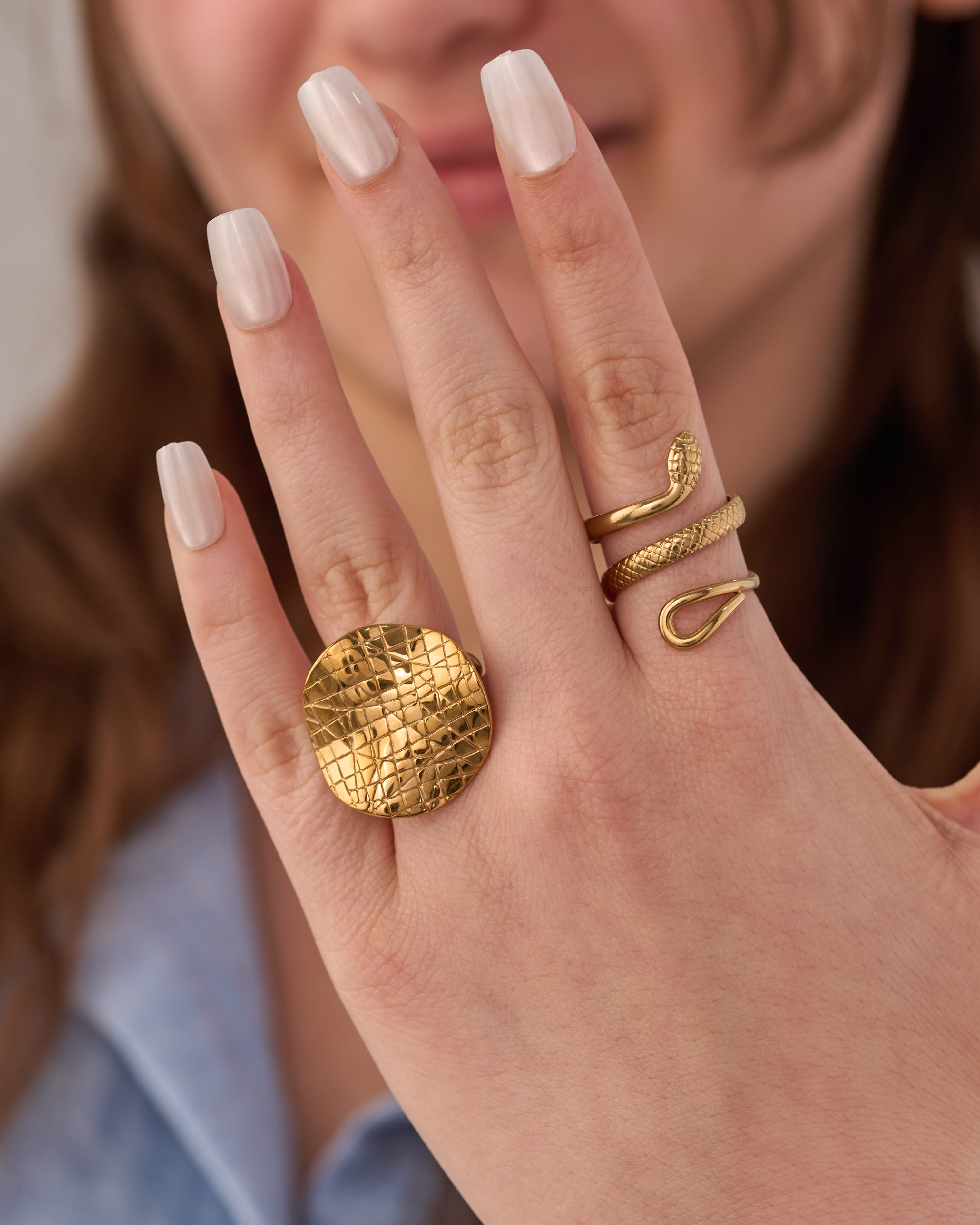 Stainless steel gold-tone statement rings set featuring snake ring and hammered disc cocktail ring on hand