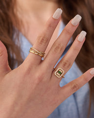 Stainless steel gold-tone twisted rope band and square halo green gemstone stacking rings worn on hand