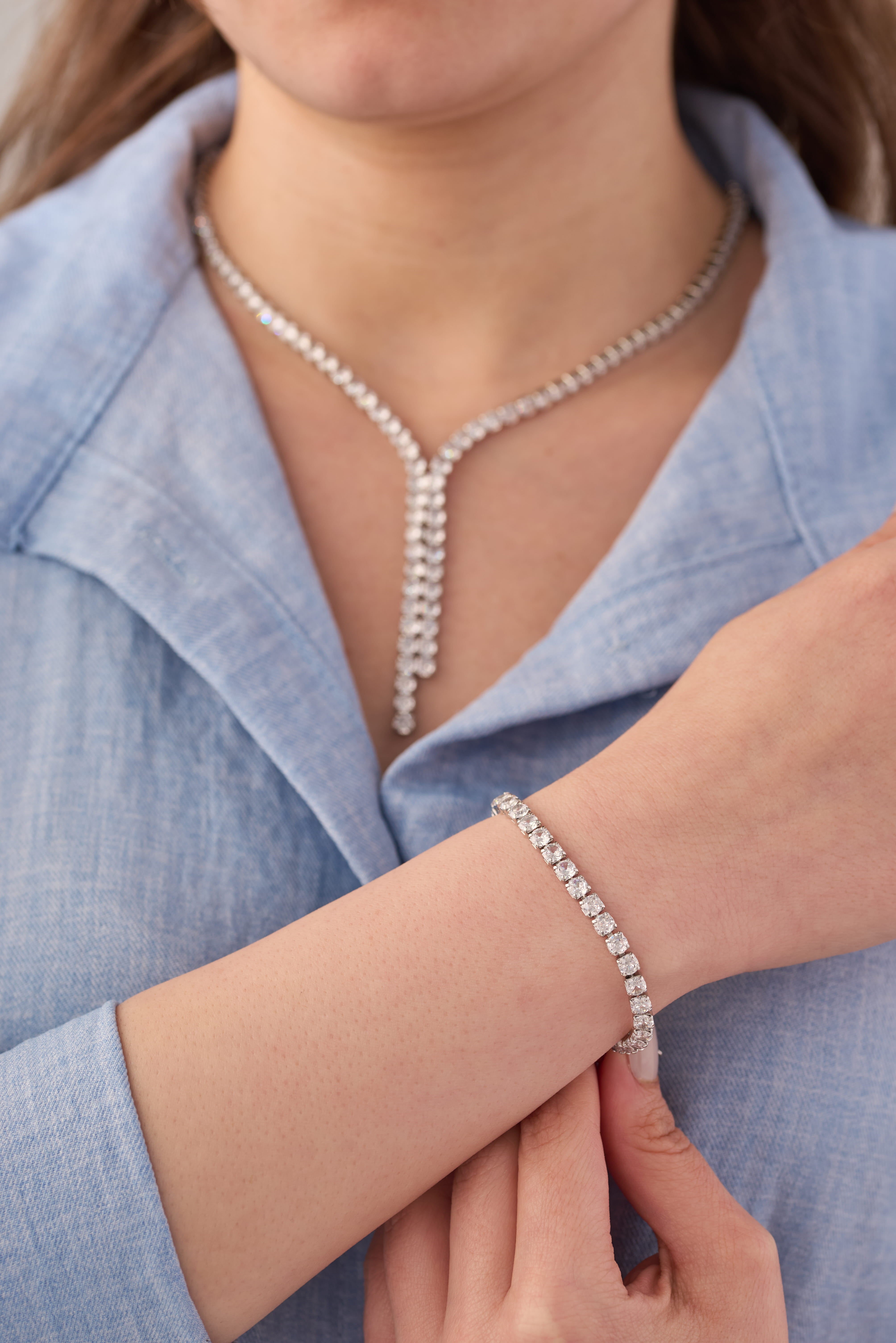 Stainless steel crystal Y-drop necklace and adjustable tennis bracelet set styled on a blue shirt