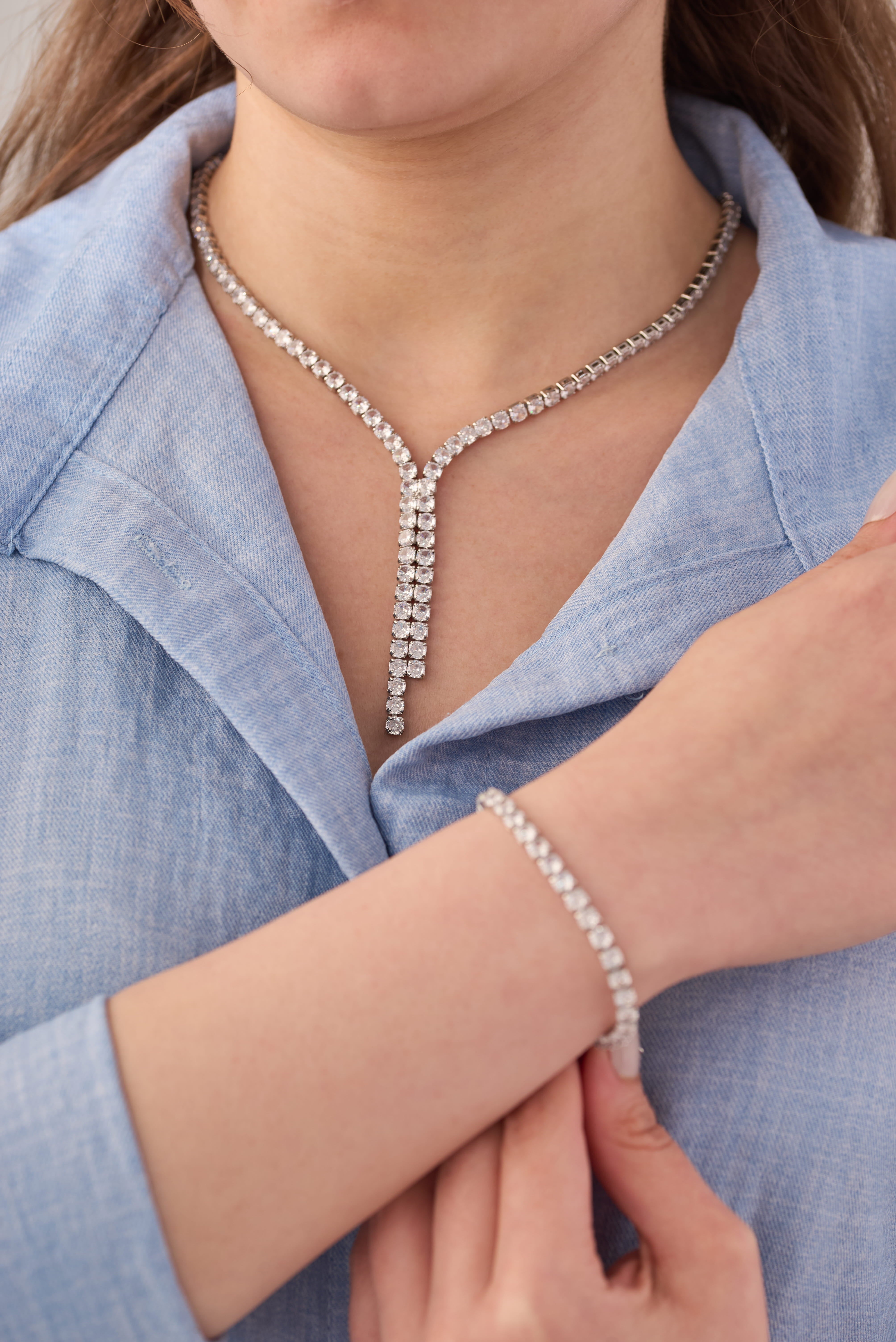 Stainless steel crystal Y-drop lariat necklace and matching tennis bracelet set worn on a light blue shirt