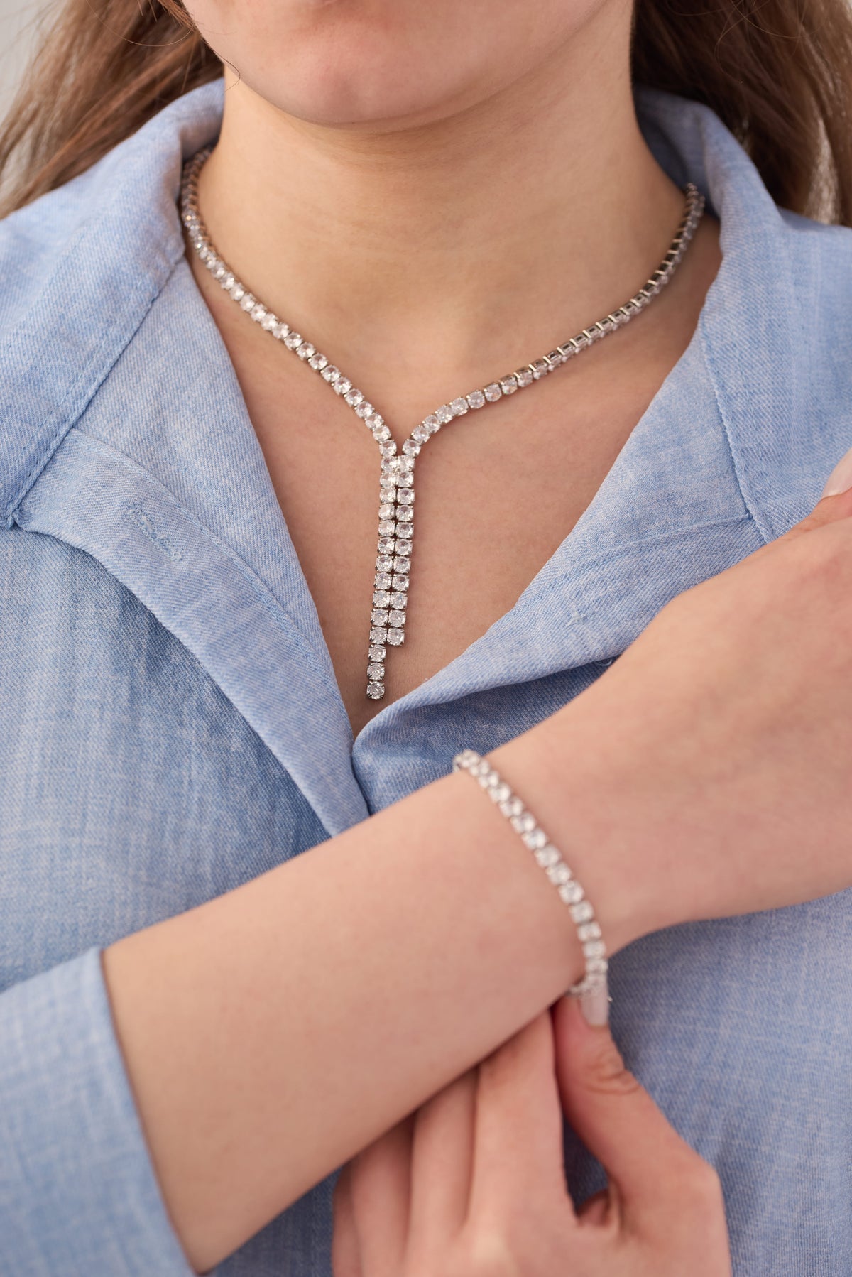 Stainless steel crystal Y-drop lariat necklace and matching tennis bracelet set worn on a light blue shirt