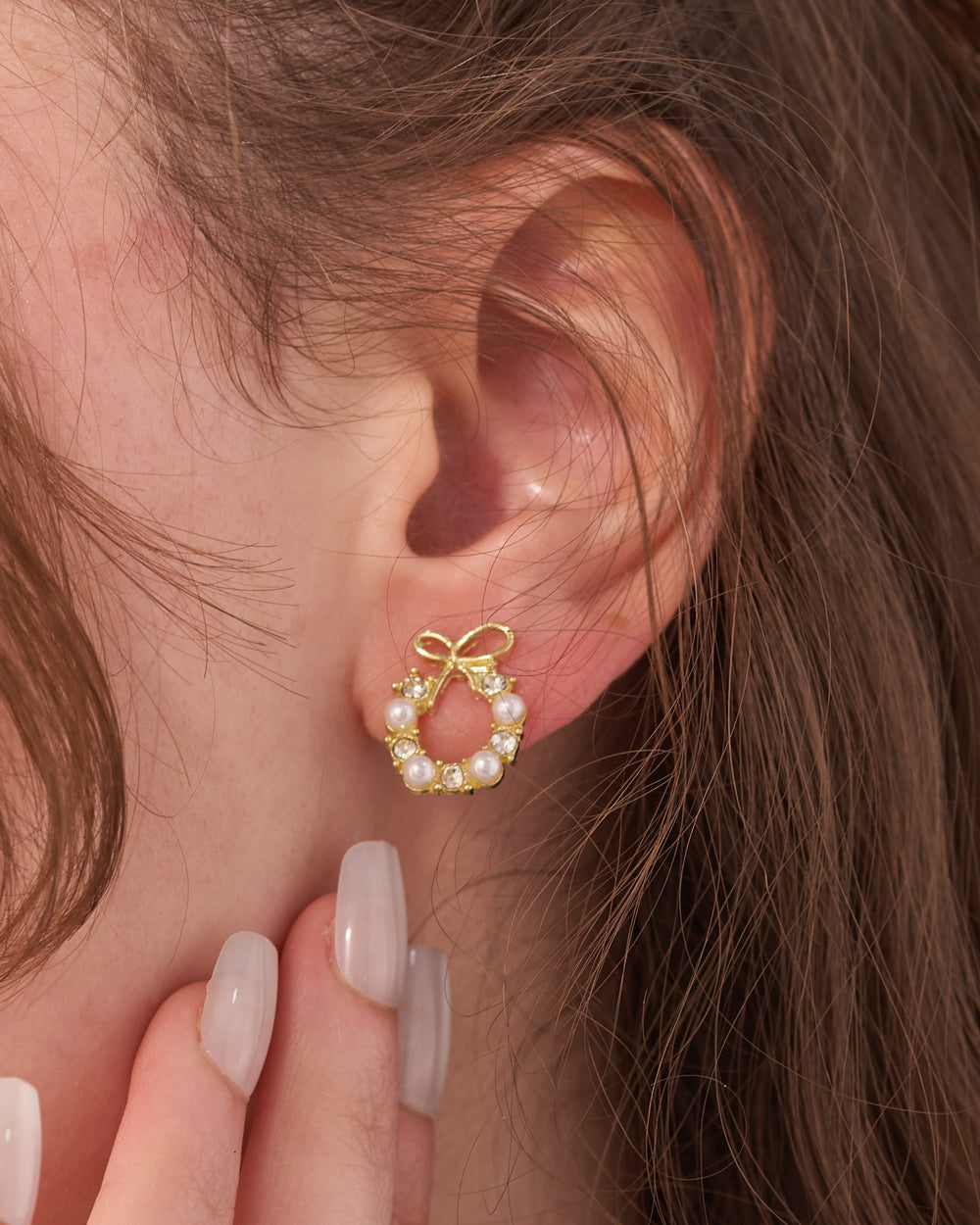 Stainless steel gold-tone bow and pearl wreath stud earring worn on ear