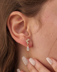 Stainless steel gold-tone star cluster stud earring with dangling crystal teardrop worn on ear
