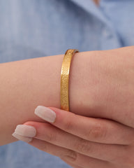 Stainless steel gold-tone textured cuff bangle bracelet on wrist