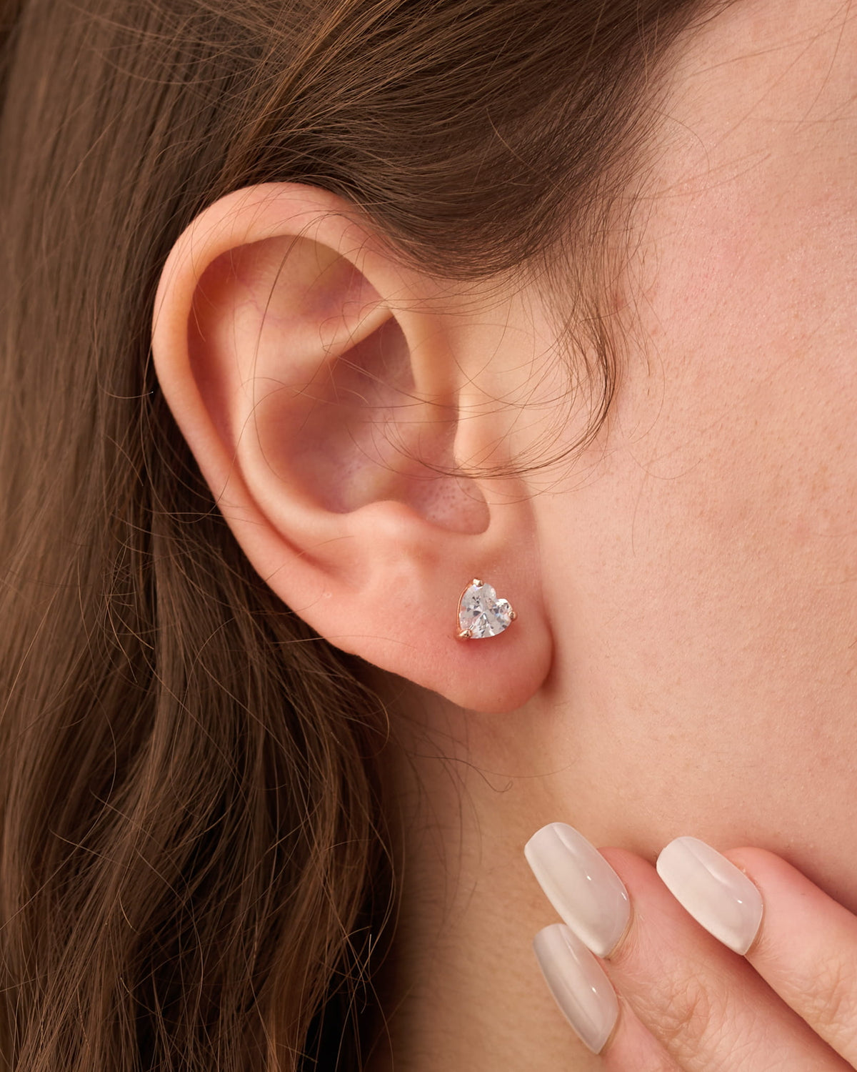 Stainless steel silver-tone heart-shaped crystal stud earring worn on ear