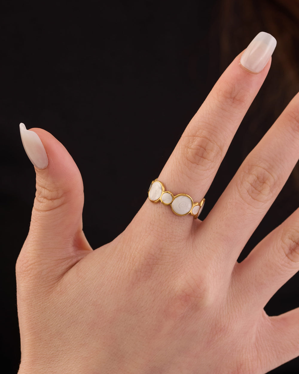 Stainless steel gold-tone triple white cabochon stone ring worn on finger