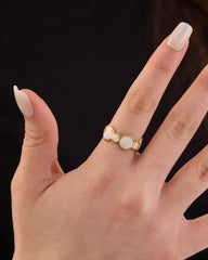 Stainless steel gold-tone triple white cabochon stone ring worn on finger