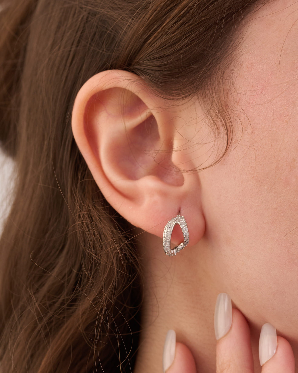 Stainless steel silver-tone open teardrop crystal drop earring worn on ear